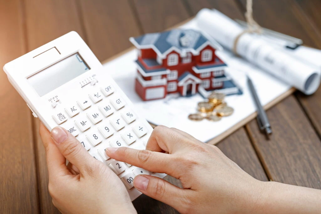 female-hand-operating-calculator-front-villa-house-model-calculating-home-loan